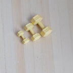 1:12 scale miniature metal hexagon dumbbells in pale yellow, set of 3 sizes, shown on a light wood surface