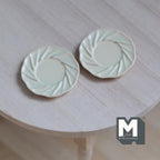 1:12 scale miniature metal dining plates in beige with a swirl embossed rim, set of 2, shown on a round wood table