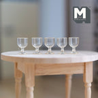1:12 scale miniature clear wine glasses with short stems, set of 5, shown in a row on a round wood table