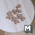1:12 scale miniature gingerbread man cookies, set of 6, brown with white icing details, non edible, on a wood table