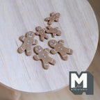 1:12 scale miniature gingerbread man cookies, set of 6, brown with white icing details, non edible, on a wood table