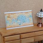 1:12 scale miniature world map print on cardstock with blue oceans and tan land, shown leaning on a wood dresser