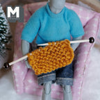 1:12 scale miniature knitting needles with knitted piece, black tipped needles, shown held by a seated figure