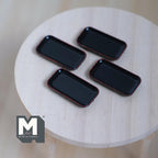 1:12 scale miniature rectangular plates in black with brown rim, set of 4, shown on a round wood table