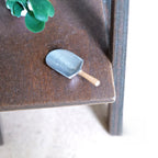1:12 scale miniature metal flour scoop in silver with wood handle, shown on a dark wood shelf