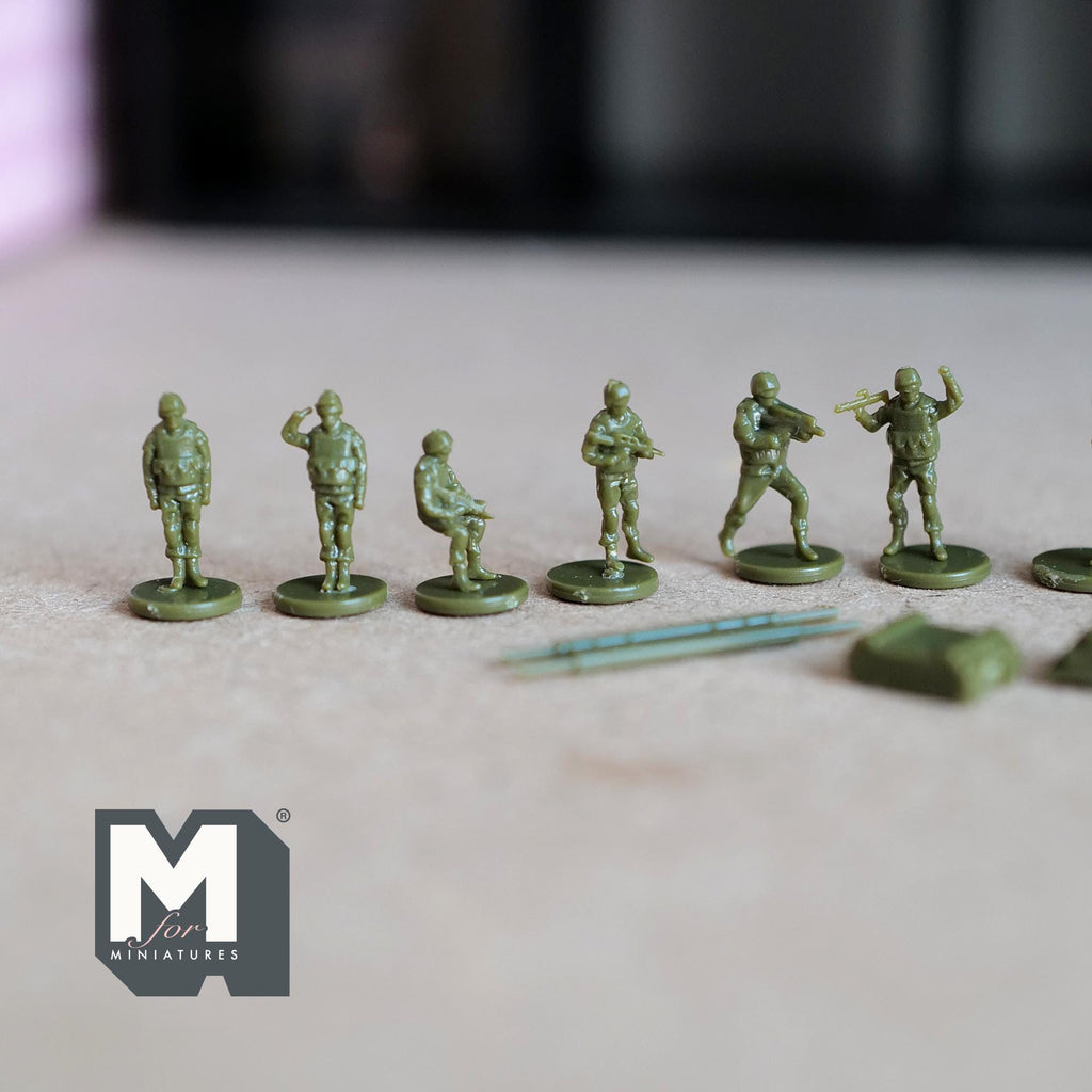 1:150 scale miniature army soldier figures in olive green, unassembled set of 16, standing in a row on a gray surface