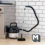 1:12 scale miniature metal canister vacuum cleaner in silver and black with hose and floor brush, in a kitchen