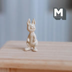 1:12 scale miniature white chocolate bunny, metal, non edible, cream colored standing rabbit shown on a wood table