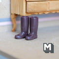 1:12 scale miniature rubber rain boots in brown, pair, shown standing on a floor beside a wood cabinet