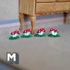 1:12 scale miniature double toadstools on grassy bases, set of 4, red caps with white spots, on a floor by a wood table
