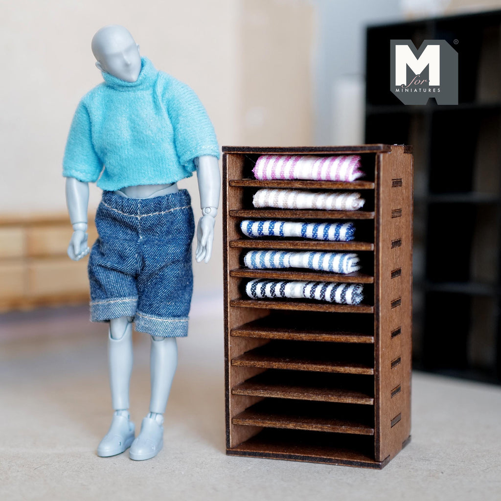 1:12 scale miniature dark brown wood fabric display shelf with folded striped textiles on cubby shelves, beside a figure