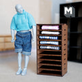 1:12 scale miniature dark brown wood fabric display shelf with folded striped textiles on cubby shelves, beside a figure