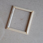 1:12 scale miniature wood photo frame with glazing and backing, ready to paint, pale natural wood on a tan surface