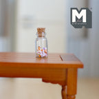 1:12 scale miniature glass jar of dolly mix candy with cork lid, pastel candies inside, shown on a wood table