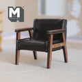 1:12 scale miniature faux leather lounge chair in dark brown, mid century modern with wood frame, on a rug