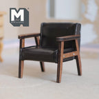 1:12 scale miniature faux leather lounge chair in dark brown, mid century modern with wood frame, on a rug