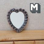 1:12 scale miniature metal heart shaped mirror with ornate antique silver frame, shown leaning on a wood dresser