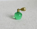 1:12 scale miniature perfume bottle in green with a gold atomizer bulb, shown on a linen surface