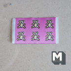1:12 scale miniature pink teddy bears rug with 6 gray bears and white edging, shown on a tan surface