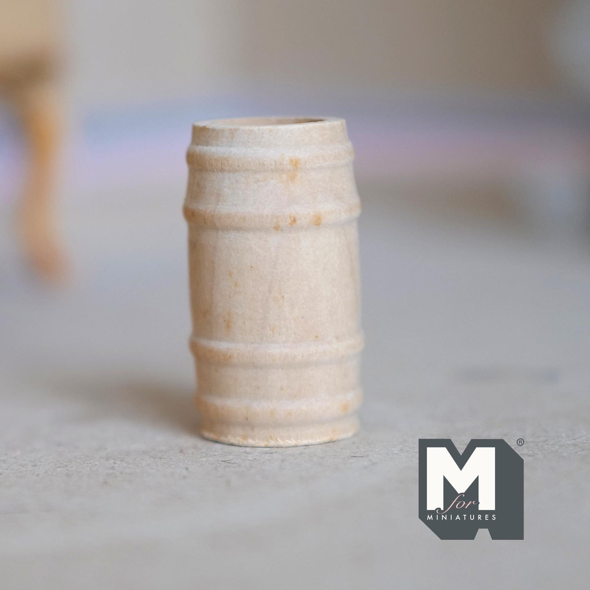 1:12 scale miniature wood wine barrel, small, unfinished pale wood with raised bands, shown on a gray floor