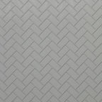 Miniature white embossed herringbone subway tile sheet with gray grout, close-up of the tile pattern