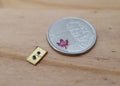 1:12 scale miniature gold wall light switch plate, rectangular, shown on a wood surface beside a coin for scale