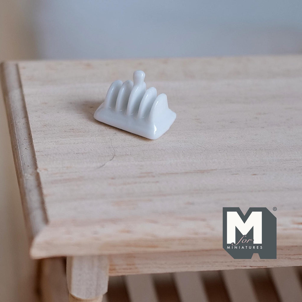 1:12 scale miniature white ceramic toast rack, shown on a light wood table