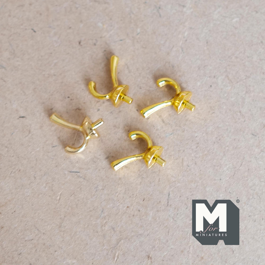 1:12 scale miniature metal wall hooks in gold with double prongs, set of 4, shown lying on a board