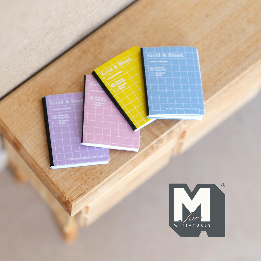 1:12 scale miniature notebooks with pastel grid covers, set of 4, purple, pink, yellow and blue, on a wood table