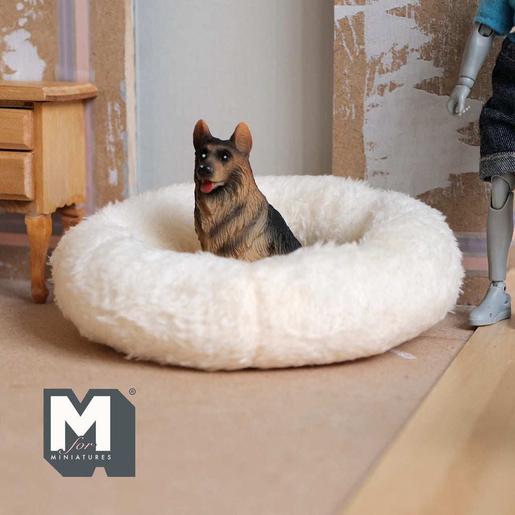 1:12 scale miniature plush dog bed in beige fabric, large round donut shape, shown with a toy German shepherd