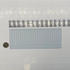 1:12 scale miniature vertical groove wainscot panel in white foamboard, shown on a tile wall with a ruler and a coin for scale