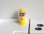 1:12 scale miniature tabletop gumball machine in yellow with a clear globe, non working, shown on a white counter