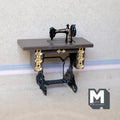 1:12 scale miniature treadle sewing machine in black with gold detail on a table with an iron look base