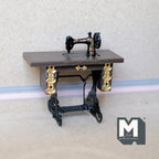 1:12 scale miniature treadle sewing machine in black with gold detail on a table with an iron look base
