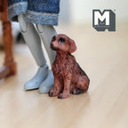 1:12 scale miniature cast resin sitting Brittany spaniel puppy in reddish brown, shown on a wood floor beside a figure's legs