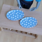 1:12 scale miniature resin oval plates in light blue with white polka dots, large, set of 2, shown on a wood table