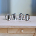1:12 scale miniature metal beer tankards with handles in silver, set of 4, shown lined up on a wood counter