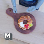 1:12 scale miniature Christmas wreath cake on a serving board, light brown with cream and berries, non edible