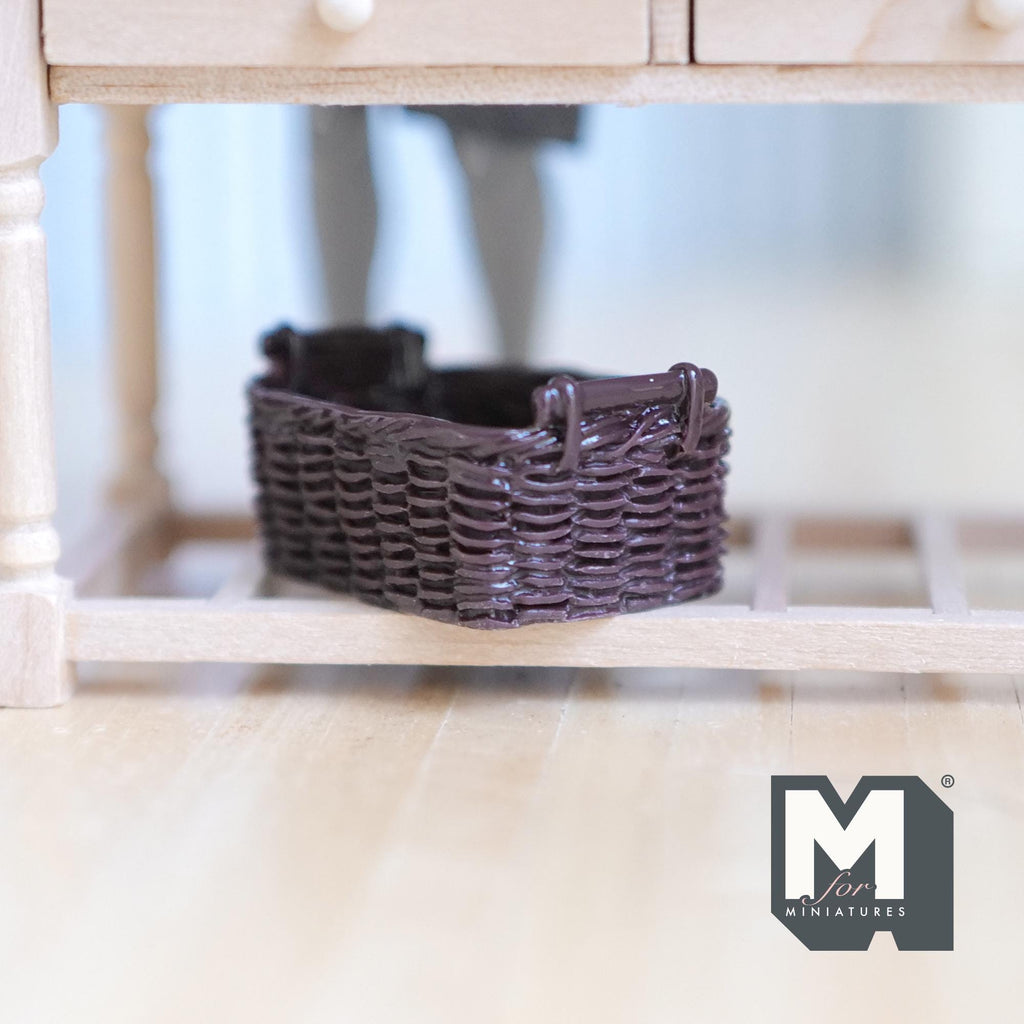 1:12 scale miniature rattan style resin basket in dark brown with handles, shown under a wood table