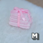 1:12 scale miniature bath towel stack in pink, set of 6, tied with a pink satin ribbon bow, shown on a white fluffy rug