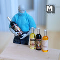 1:12 scale miniature large wine bottles with printed labels, set of 4, shown with an artist figure holding one