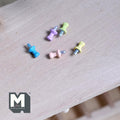 1:12 scale miniature push pins in assorted pastel colors, set of 5, scattered on a light wood surface