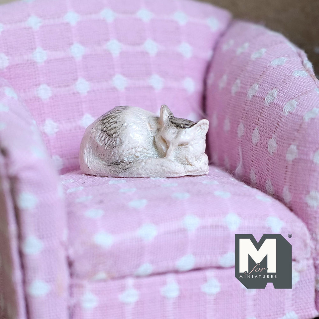 1:12 scale miniature sleeping cat, curled up, white and tabby, shown on a pink dotted armchair