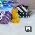 1:12 scale miniature sitting bunny doll in yellow flocked finish with upright ears, on a white rug beside wrapped gifts