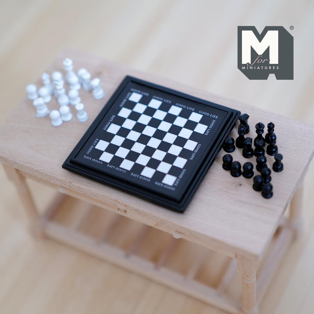1:12 scale miniature chess set with black board and black and white pieces, non magnetic, laid out on a wood table
