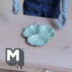 1:12 scale miniature 3 compartment dish in green with scalloped edge and silver center handle, on a wood table