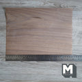 Miniature walnut peel and stick wood veneer sheet, dark brown natural grain, shown with a ruler on a gray wood surface