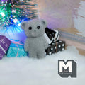 1:12 scale miniature bear cub doll in gray with flocked skin, shown with wrapped gifts under a lit tree