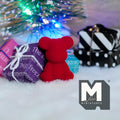 1:12 scale miniature bear cub in red with flocked skin, shown sitting among gift boxes under a Christmas tree