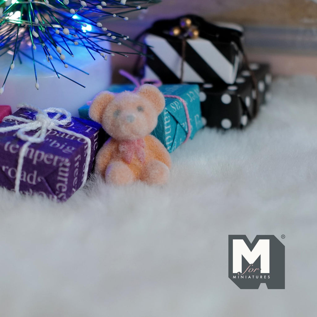 1:12 scale miniature bear cub doll in beige and orange flocked finish, sitting on a white rug by wrapped gifts